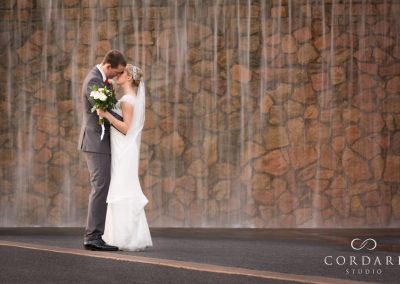 Bride and groom kissing by waterfall