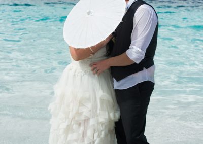 bride and groom kiss behind umbrella